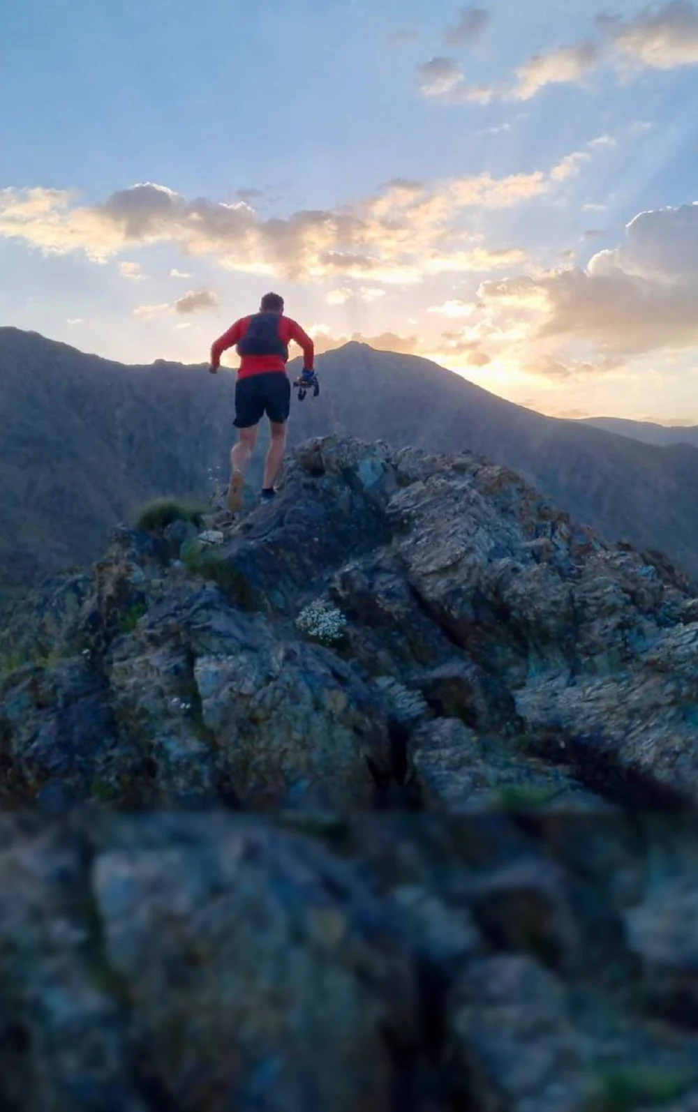 Runner traversing a rocky mountain ridge at sunset