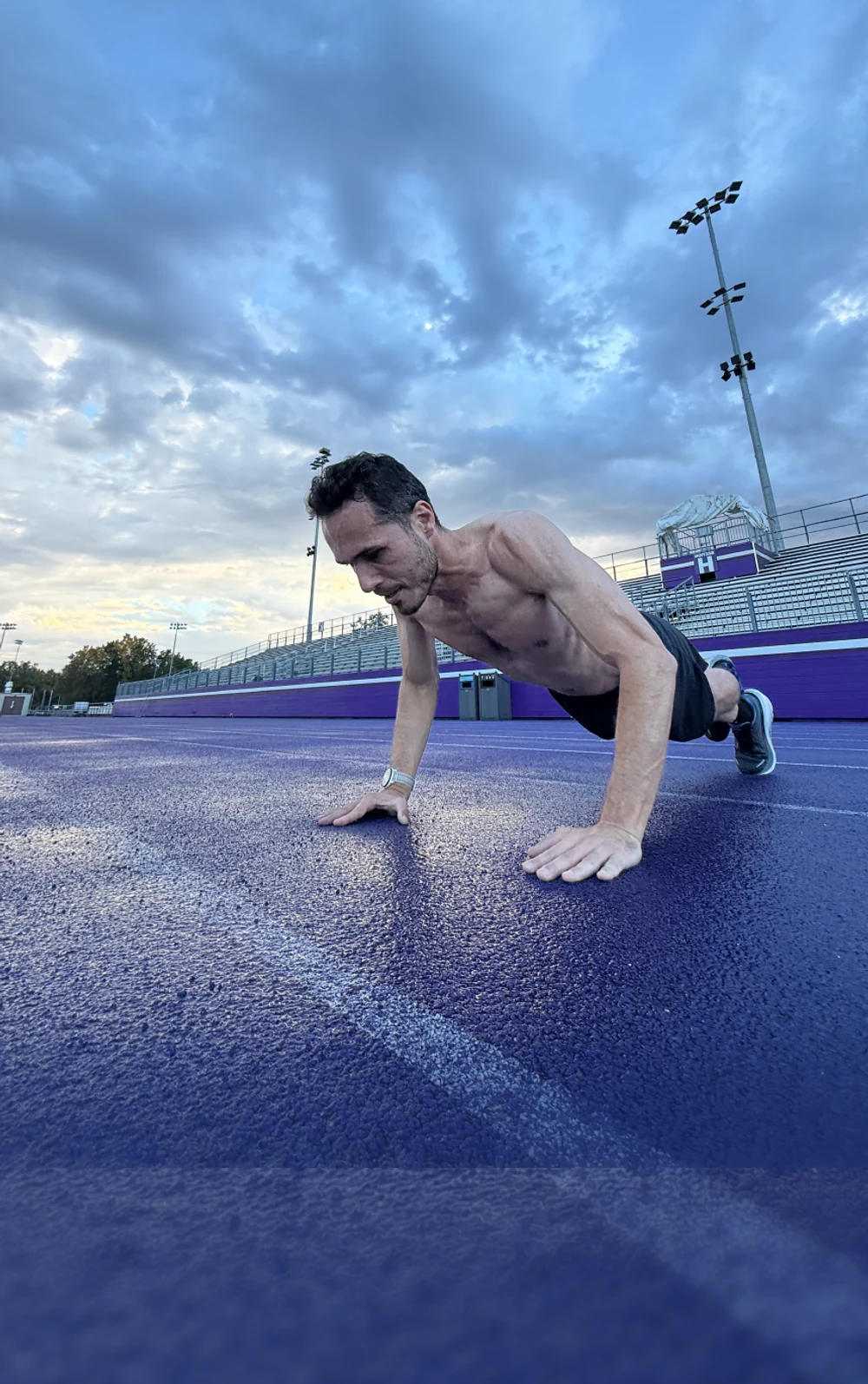 Athlete doing a push-up beside an outdoor running track